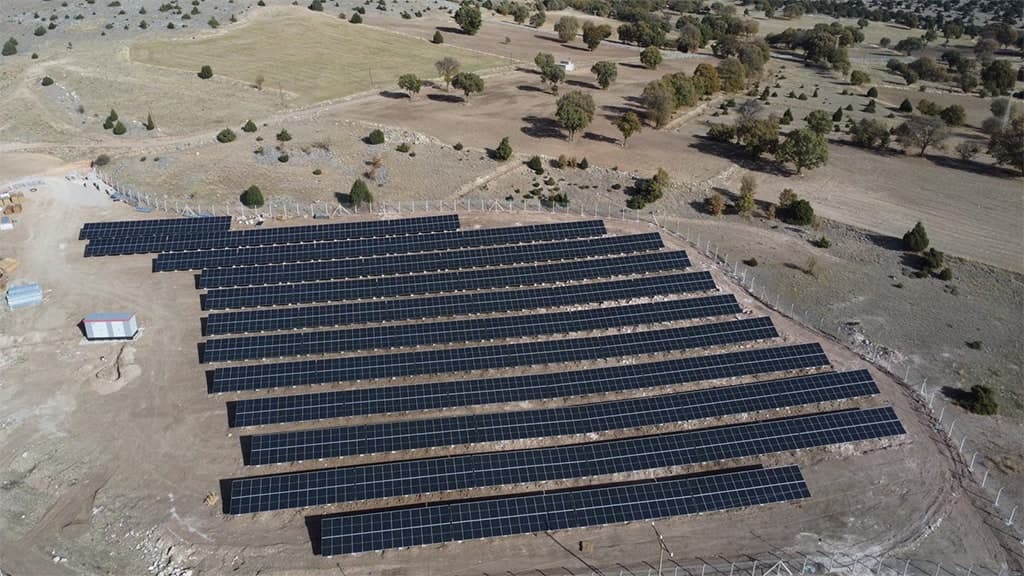 Aerial view of ground-mounted solar array rows on open land